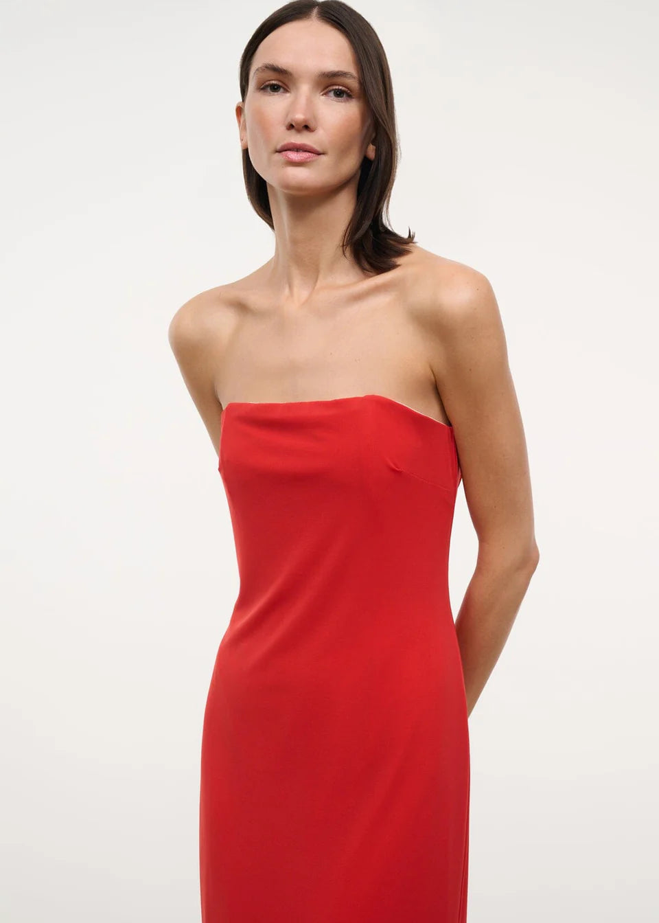 A person wearing a solid red strapless midi Liliana Dress for special occasions.