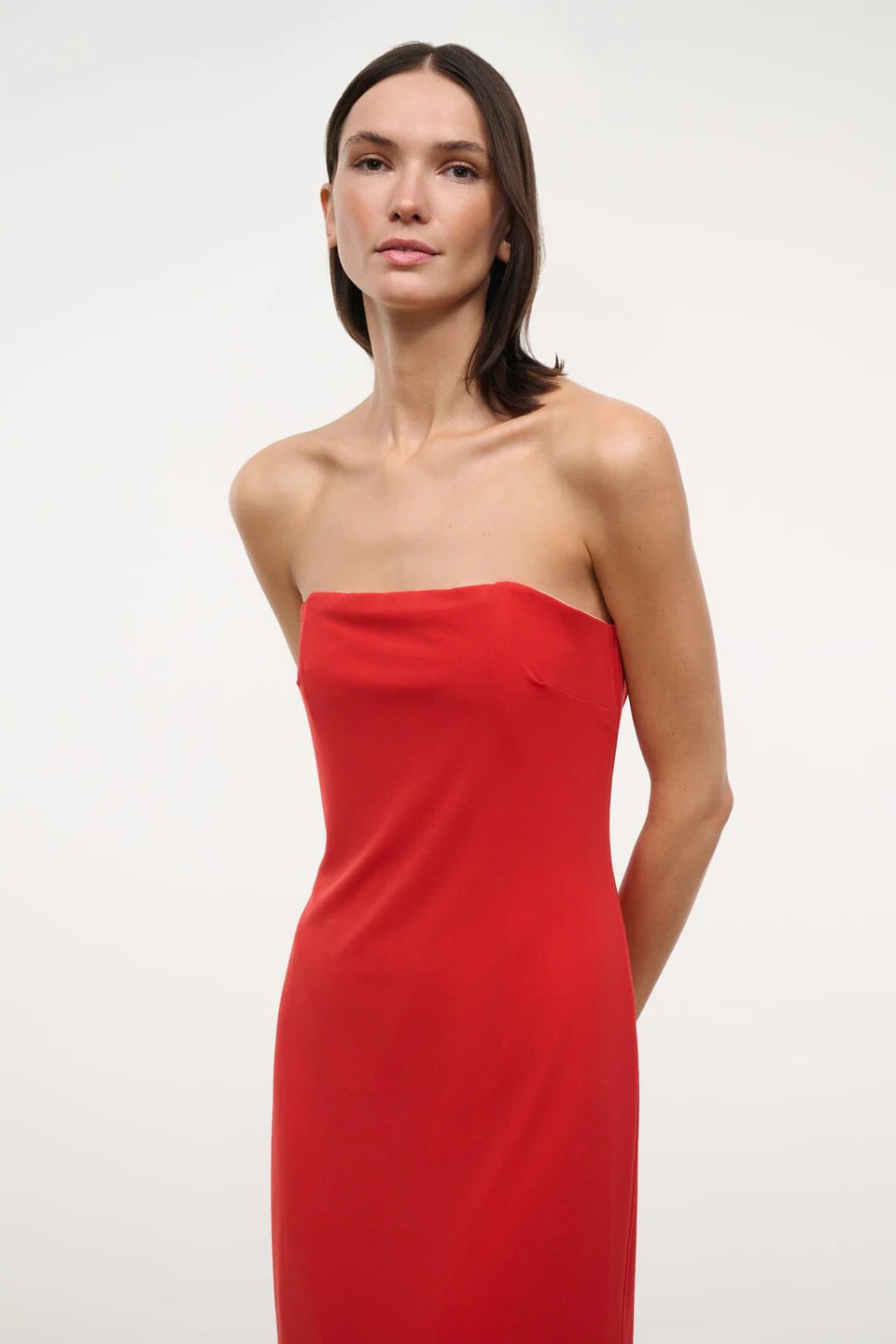 A person wearing a solid red strapless midi Liliana Dress for special occasions.