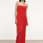 A person wearing a red, floor-length, strapless Liliana Dress with a sheer overlay.