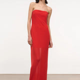 A person wearing a red, floor-length, strapless Liliana Dress with a sheer overlay.