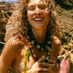 KABE SHOP INC Tesoro necklace featuring mixed natural beads of wood, coconut, seashell, and stone on a smiling woman