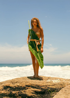 KABE SHOP INC Jibe belt featuring natural shell adornments worn by a woman on a beach with a large tropical leaf