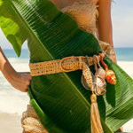KABE SHOP INC Jibe belt in natural woven fiber with removable seashell charms and tassel, worn on a beach.