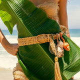 KABE SHOP INC Jibe belt in natural woven fiber with removable seashell charms and tassel, worn on a beach.