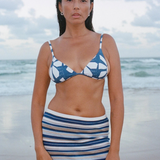 KABE SHOP INC Geo Flower triangle bikini top with blue and white floral print worn by a woman on a beach
