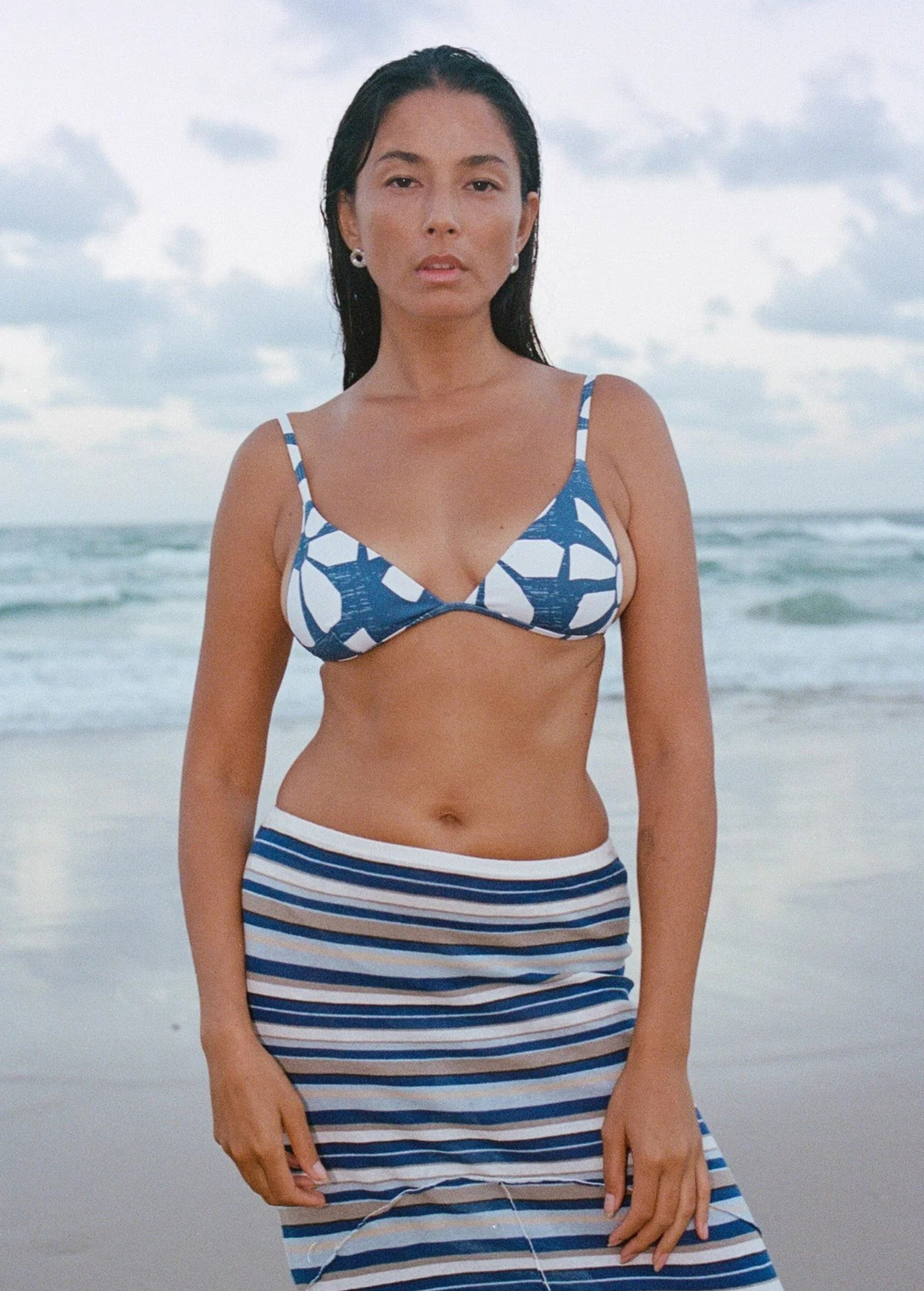 KABE SHOP INC Geo Flower triangle bikini top with blue and white floral print worn by a woman on a beach