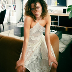 Model wearing a KABE SHOP INC upcycled vintage lace handkerchief dress with a halter neck in a modern living room.