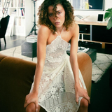 Model wearing a KABE SHOP INC upcycled vintage lace handkerchief dress with a halter neck in a modern living room.