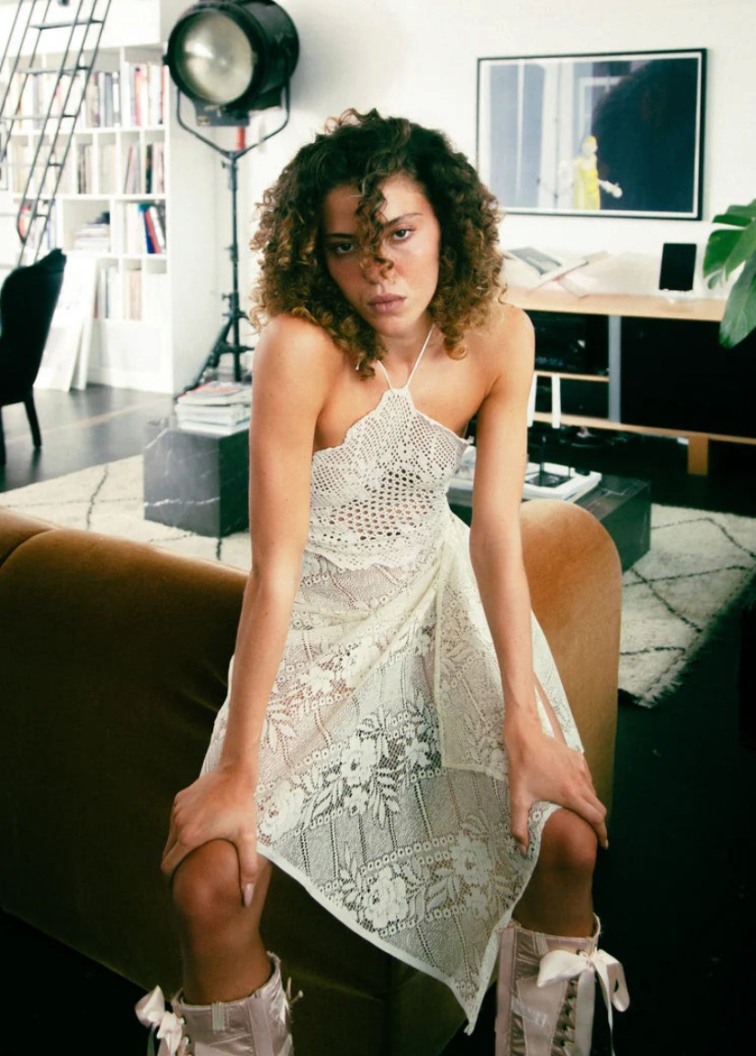 Model wearing a KABE SHOP INC upcycled vintage lace handkerchief dress with a halter neck in a modern living room.