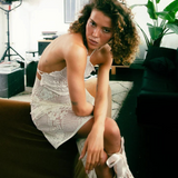 KABE SHOP INC upcycled white lace handkerchief dress worn by a model with curly hair sitting on a brown sofa