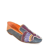 The Anzu Moccasin is a hand-embroidered leather loafer crafted with blue textured material, multicolored beaded designs on the upper, tan leather detailing at the heel, and an orange interior.