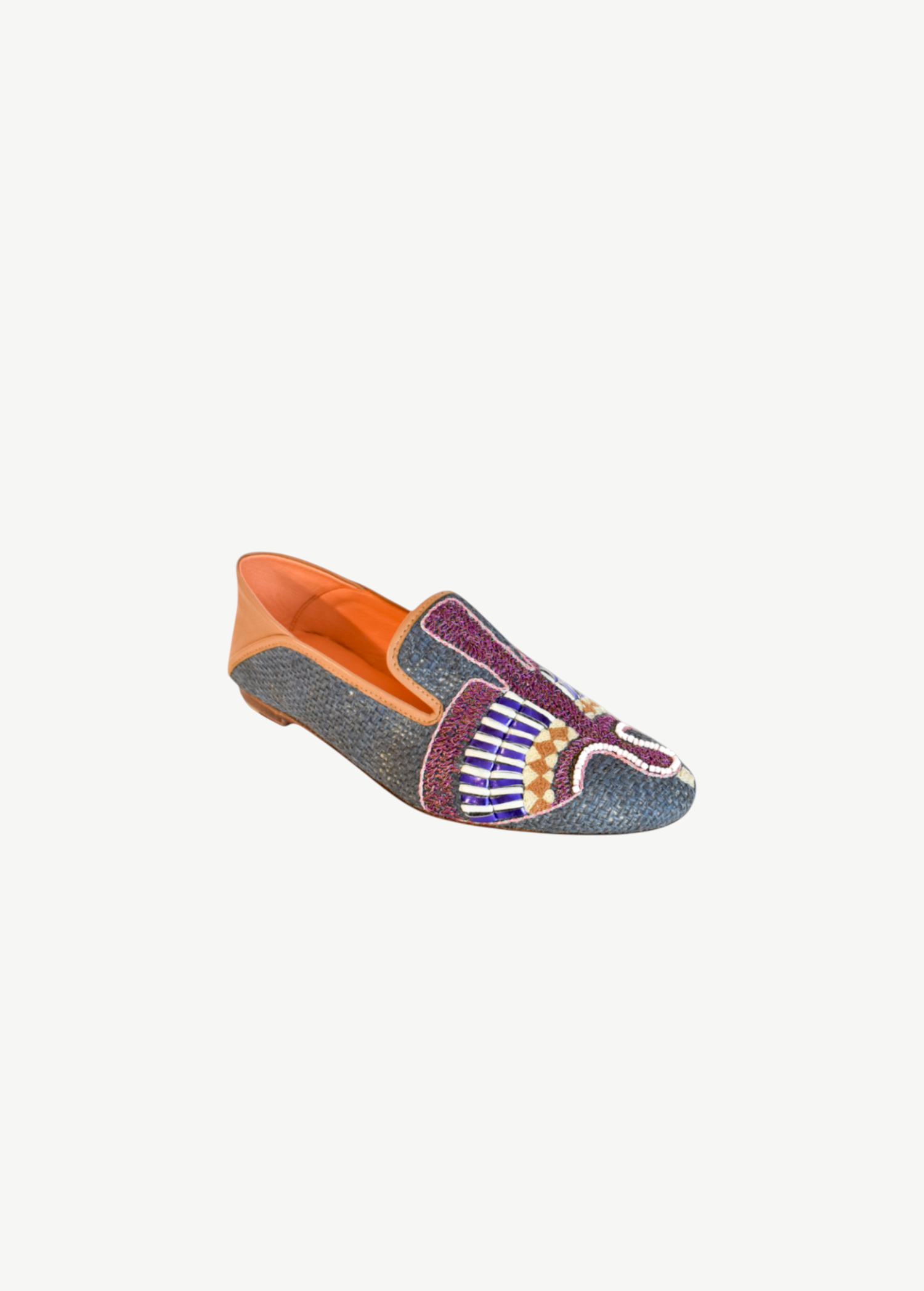 The Anzu Moccasin is a hand-embroidered leather loafer crafted with blue textured material, multicolored beaded designs on the upper, tan leather detailing at the heel, and an orange interior.