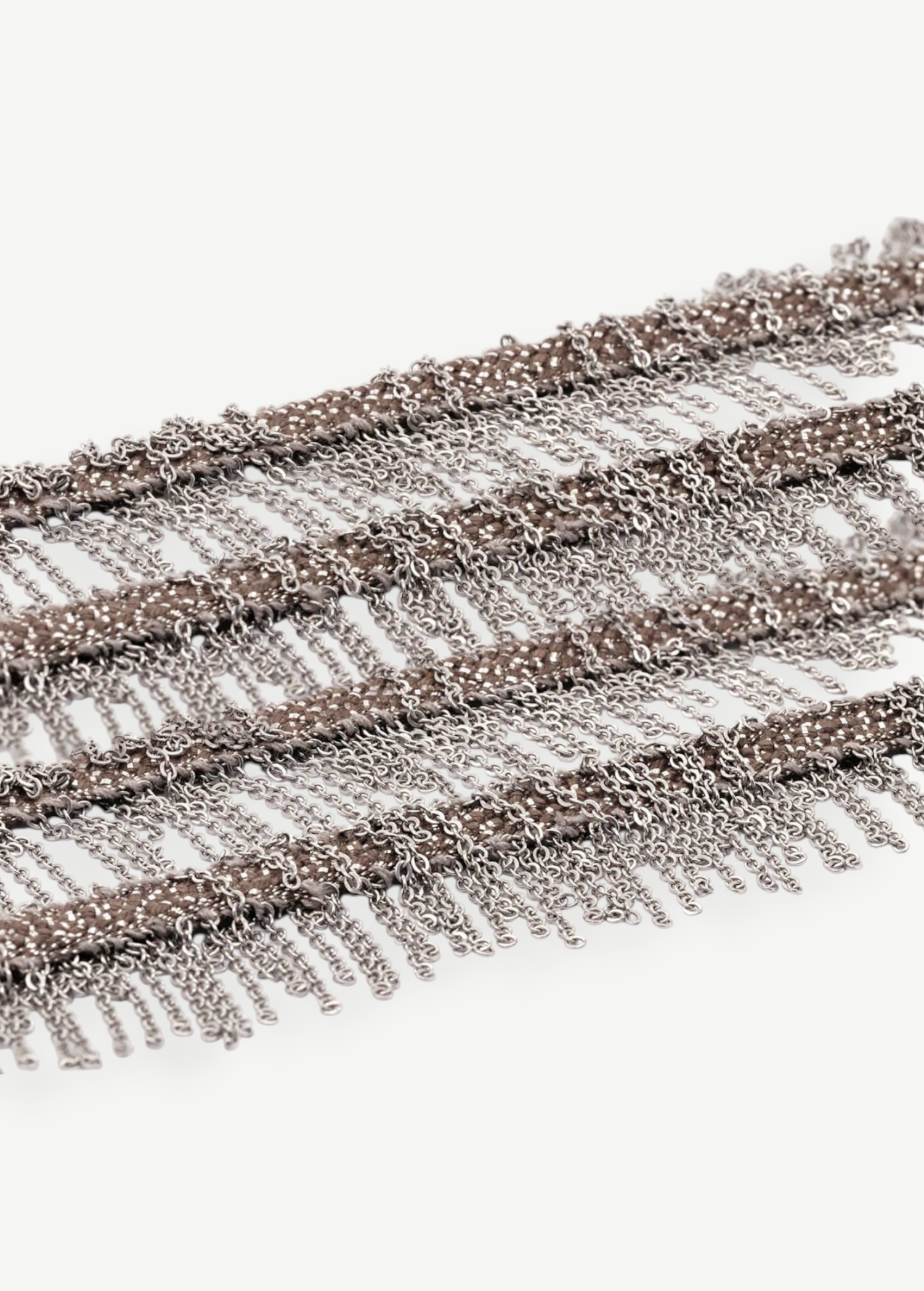 Close-up of several rows of thin metallic chains in white bronze hanging in layers, creating a fringe pattern reminiscent of the Lariat Necklace White Bronze, set against a white background.
