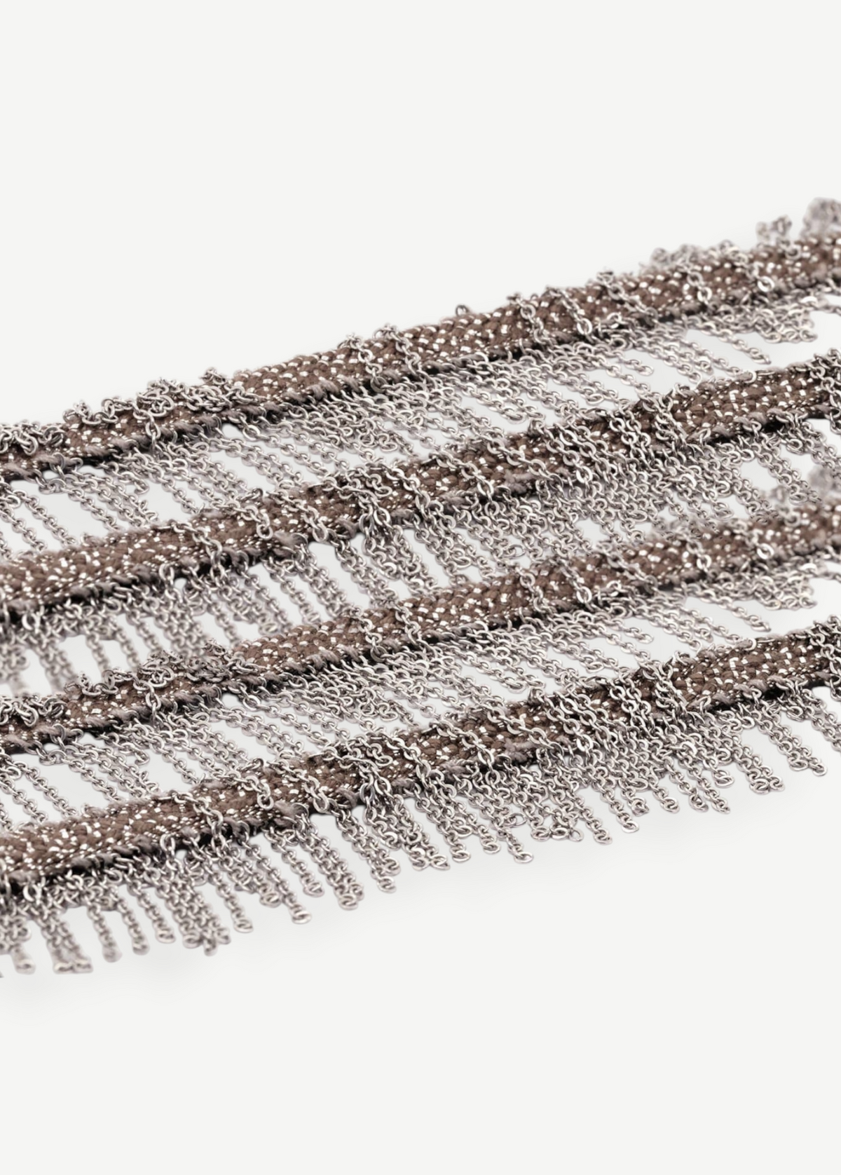 Close-up of several rows of thin metallic chains in white bronze hanging in layers, creating a fringe pattern reminiscent of the Lariat Necklace White Bronze, set against a white background.