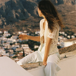 KABE SHOP INC Poolside Top in cream cotton crochet with open-weave texture worn by a woman overlooking a town