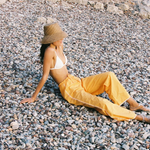 KABE SHOP INC Casa Pant in yellow organic cotton with wide-leg fit and crochet side detail on a pebble beach