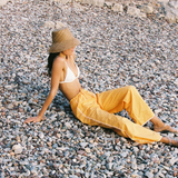 KABE SHOP INC Casa Pant in yellow organic cotton with wide-leg fit and crochet side detail on a pebble beach