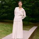 A person wearing a cream v-neck Kiki Shirt with thin vertical stripes, paired with a matching maxi skirt in a romantic silhouette.