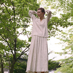 A person stands outdoors wearing an elegant Kiki Shirt and matching maxi skirt, both featuring thin vertical stripes in a romantic silhouette.
