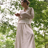A person wearing a Kiki Shirt paired with a matching pleated skirt in cream fabric with thin metallic detailing, creating an elegant statement silhouette.