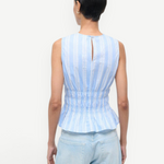 Back view of the Culver Top, a feminine, sleeveless blue and white striped peplum top with a smocked waist and a small keyhole opening at the nape of the neck for a flattering silhouette.