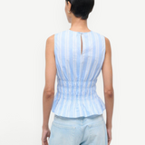 Back view of the Culver Top, a feminine, sleeveless blue and white striped peplum top with a smocked waist and a small keyhole opening at the nape of the neck for a flattering silhouette.