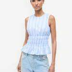 Culver Top in a light blue and white striped sleeveless peplum style with a smocked waist for a feminine silhouette.