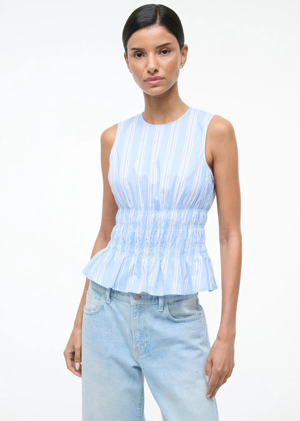 Culver Top in a light blue and white striped sleeveless peplum style with a smocked waist for a feminine silhouette.