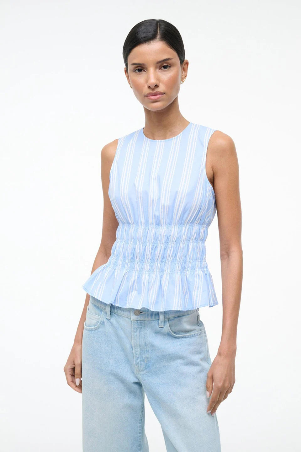 Culver Top in a light blue and white striped sleeveless peplum style with a smocked waist for a feminine silhouette.