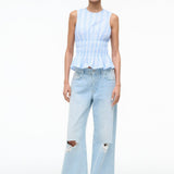 Culver Top featuring a sleeveless, blue-and-white striped peplum design with a smocked waist, paired with light-wash, ripped wide-leg jeans.