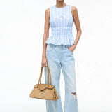 A model wears the light blue and white striped Culver Top with a sleeveless, smocked-waist silhouette, paired with light-wash distressed jeans and a tan handbag for a feminine style.