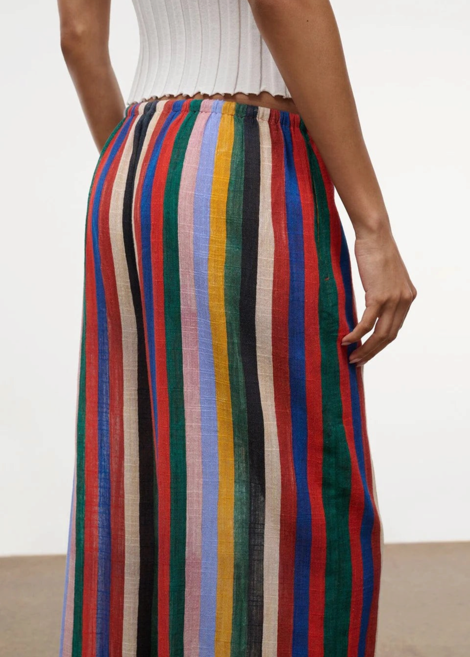 Wide-leg Mateo Pant with a colorful vertical stripe pattern and an elastic waistband, worn with a white ribbed top as a relaxed, warm-weather essential.