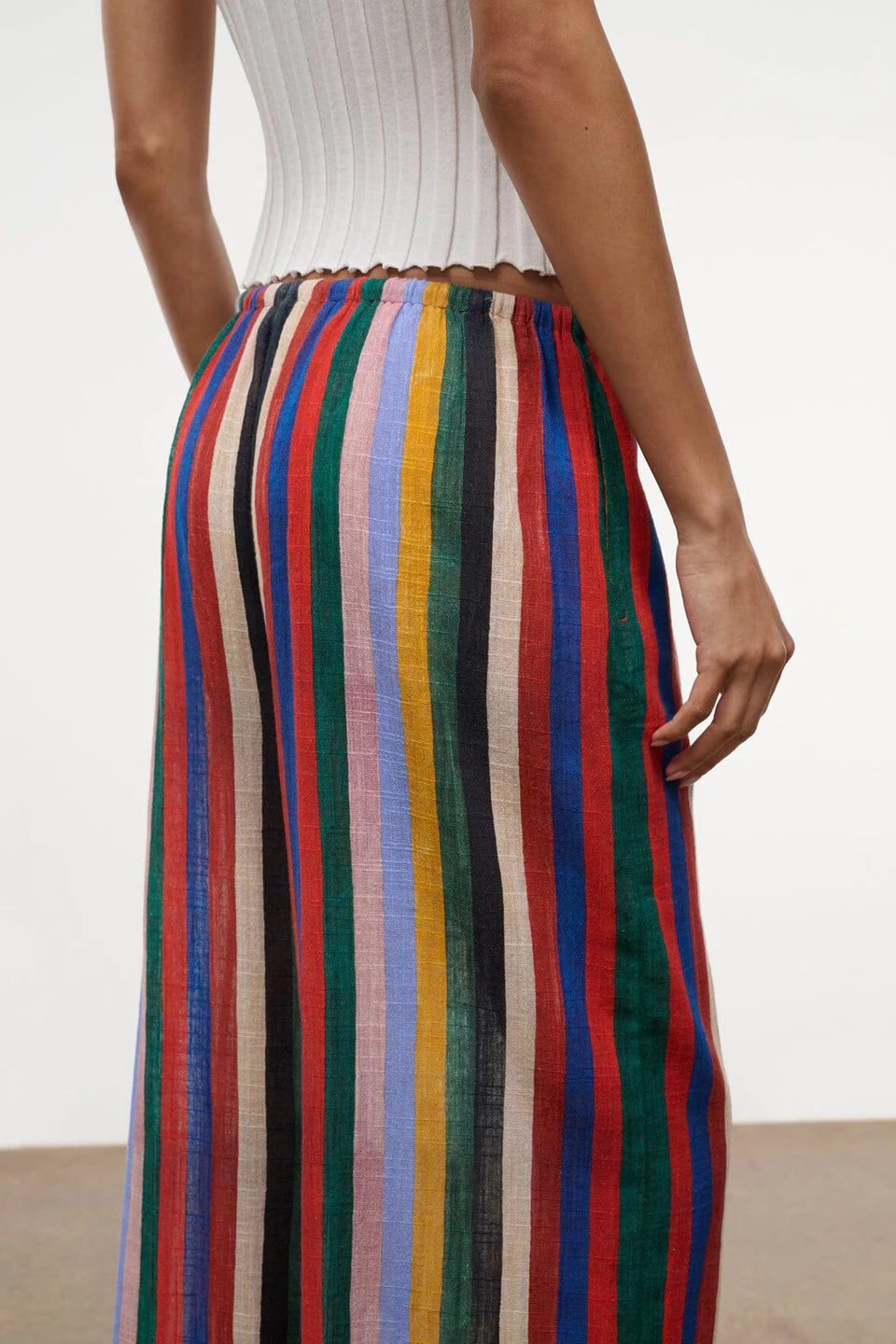 Wide-leg Mateo Pant with a colorful vertical stripe pattern and an elastic waistband, worn with a white ribbed top as a relaxed, warm-weather essential.