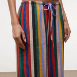 High-waisted, wide-leg Mateo pants featuring a colorful vertical stripe pattern, a drawstring waist, and a relaxed fit perfect for warm weather.