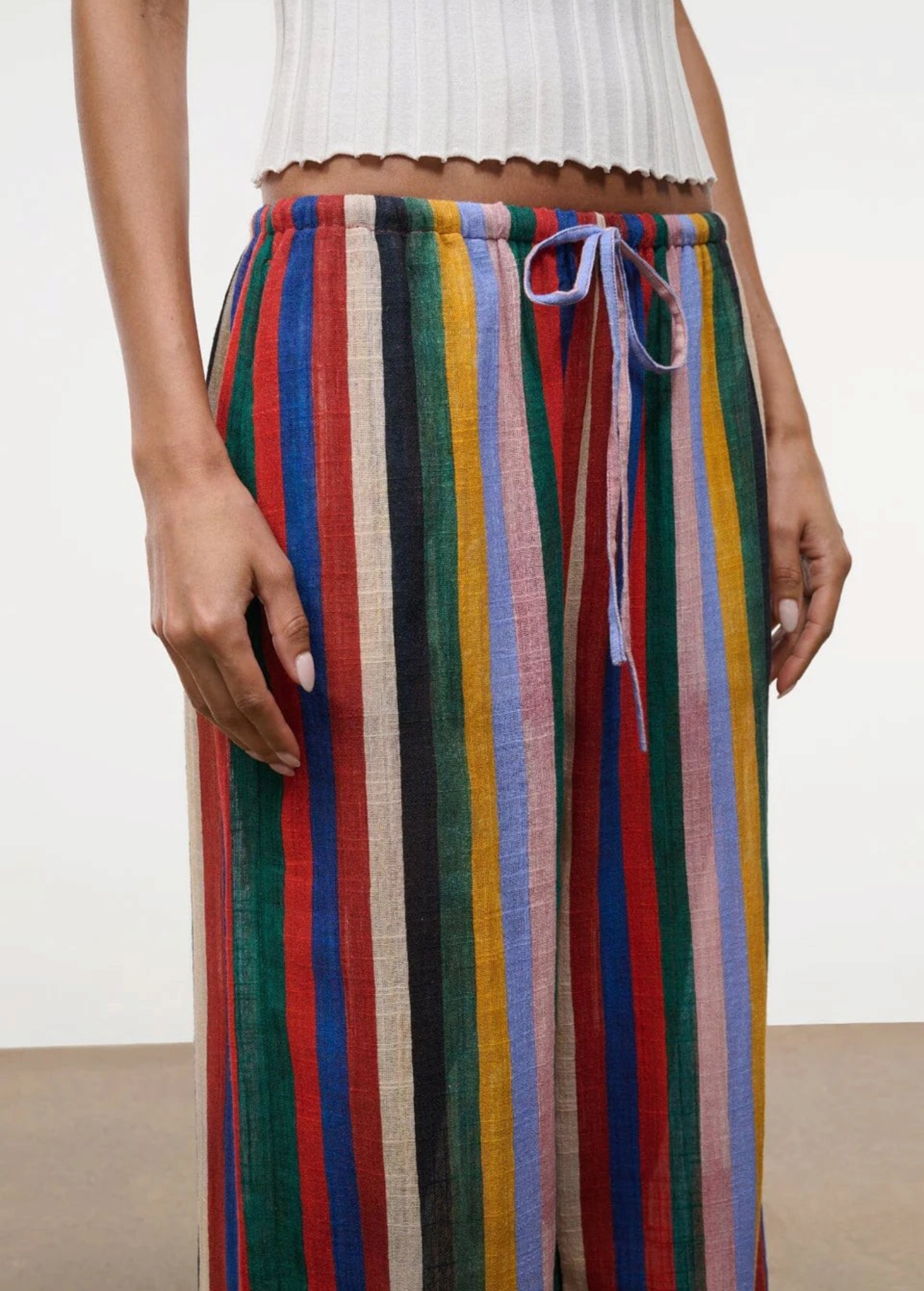High-waisted, wide-leg Mateo pants featuring a colorful vertical stripe pattern, a drawstring waist, and a relaxed fit perfect for warm weather.