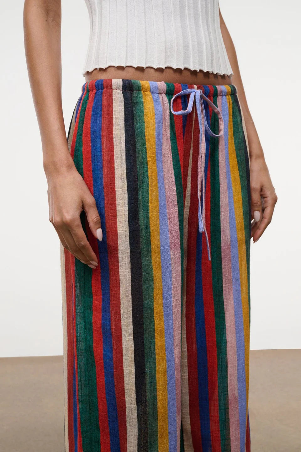 High-waisted, wide-leg Mateo pants featuring a colorful vertical stripe pattern, a drawstring waist, and a relaxed fit perfect for warm weather.