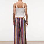 Back view of a person in a white ribbed tank top and Mateo Pant wide-leg trousers featuring vertical multicolored stripes.