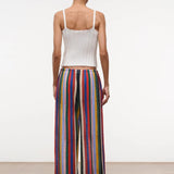 Back view of a person in a white ribbed tank top and Mateo Pant wide-leg trousers featuring vertical multicolored stripes.