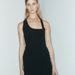 Model wearing a KABE SHOP INC black asymmetric racer mini slip dress with a body-hugging fit against a white wall.