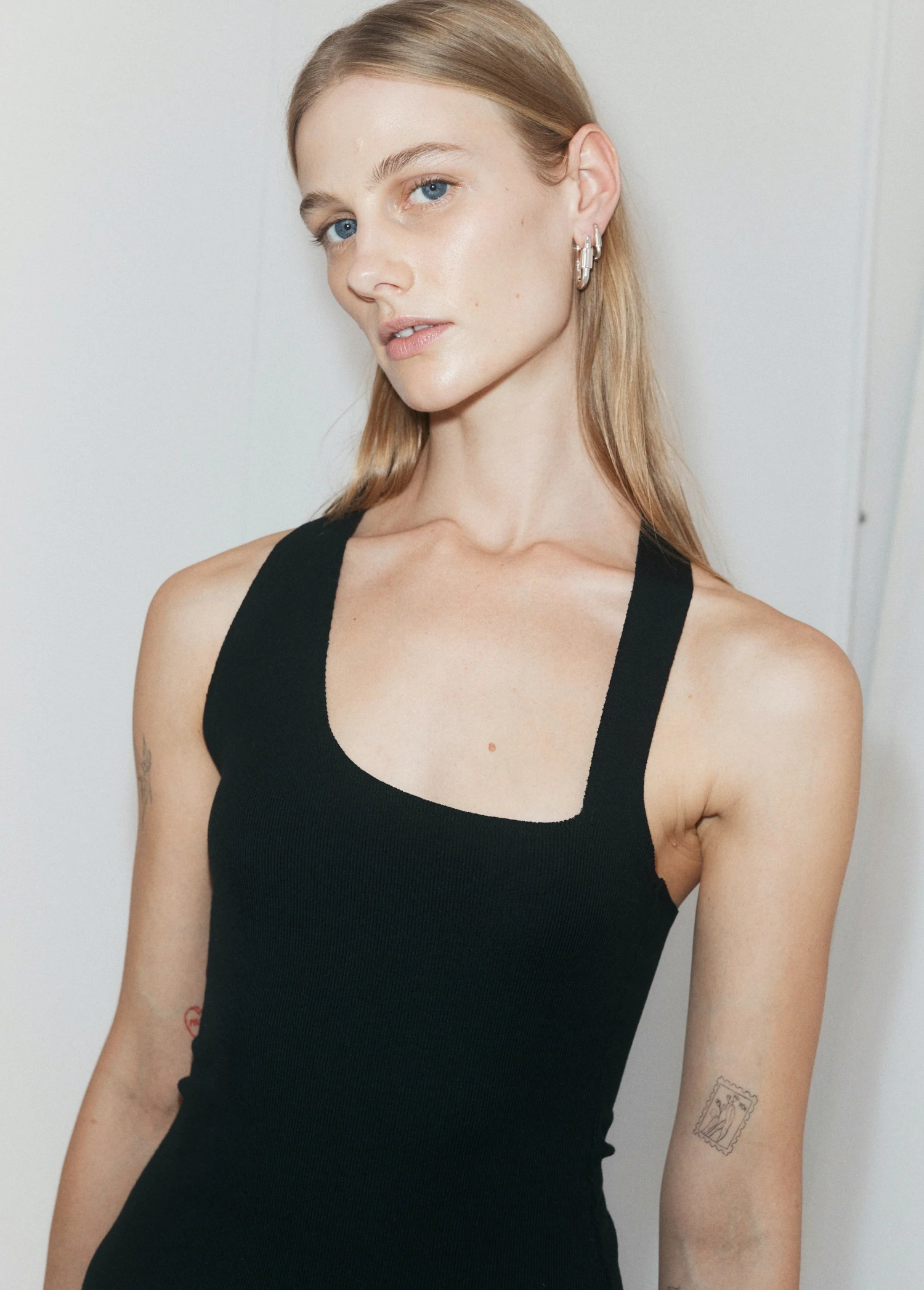 Model wearing a black KABE SHOP INC asymmetric racer slip dress with a ribbed texture and body-hugging fit.