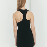 Back view of a woman wearing a KABE SHOP INC black asymmetric racerback mini slip dress with a body-hugging fit.