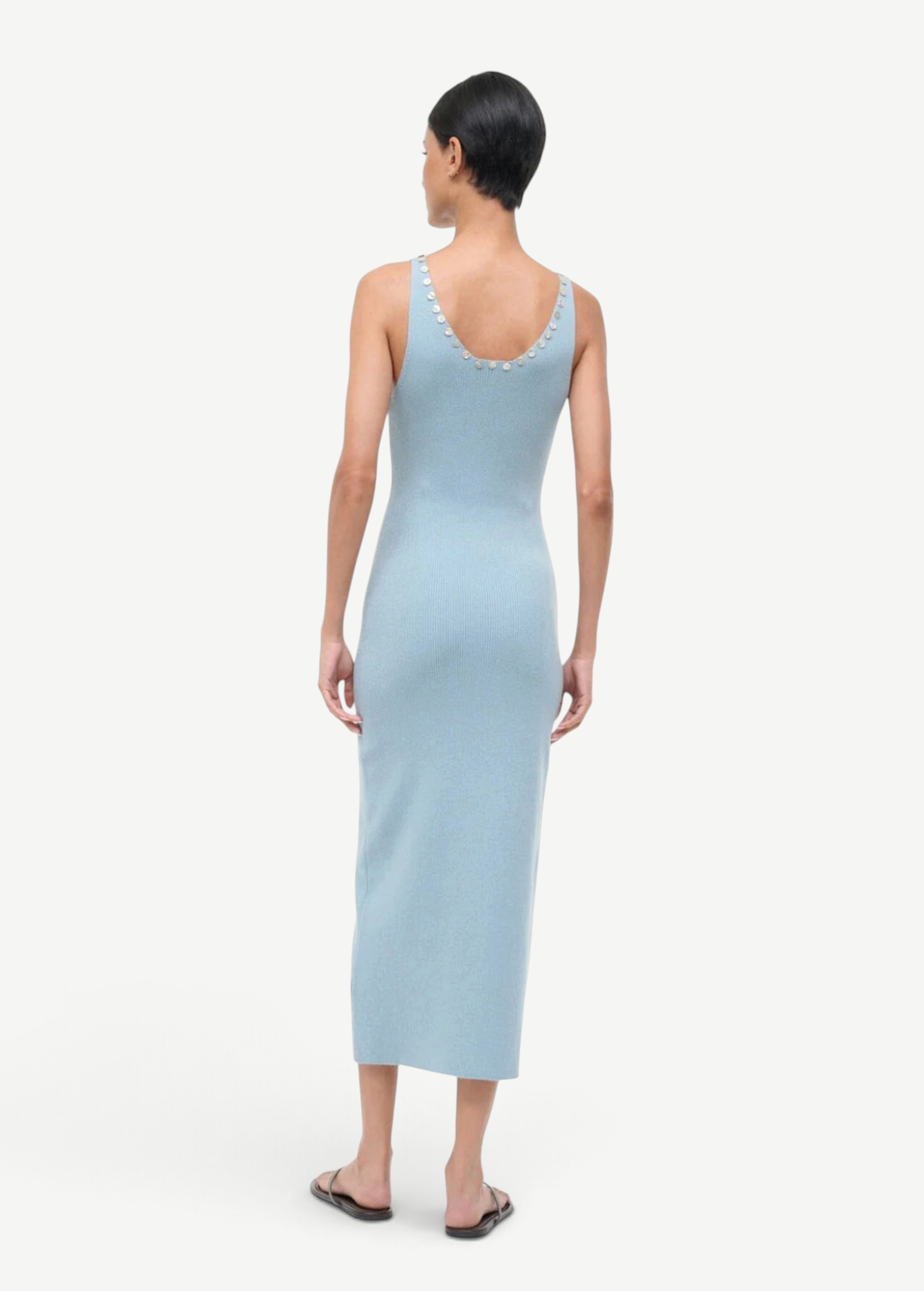 Back view of the Neva Dress, a sophisticated, light blue ribbed midi dress with circular button details along the back neckline for a timeless style.
