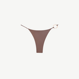 The Orb Luna Bottom is a brown high-cut bikini bottom crafted from ECONYL® regenerated nylon, featuring thin adjustable straps and a decorative gold ring detail on the right side, displayed on a white background.