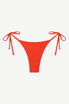 Praia Bottom in bright red, featuring a tie-side design with minimal back coverage, crafted from compression fabric and displayed against a plain white background.