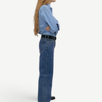 Model wearing KABE SHOP INC Everyday Jeans in a relaxed blue denim fit, styled with a light blue shirt and belt.