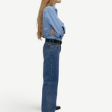 Model wearing KABE SHOP INC Everyday Jeans in a relaxed blue denim fit, styled with a light blue shirt and belt.