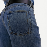 KABE SHOP INC Everyday Jeans in medium wash denim with a back pocket featuring SH embroidery and a black leather belt.