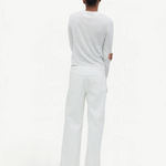 A person with short dark hair stands facing away, wearing a long-sleeve white shirt and the Cool Jean—a relaxed leg jean featuring an adjustable drawstring waist—set against a plain, light background.