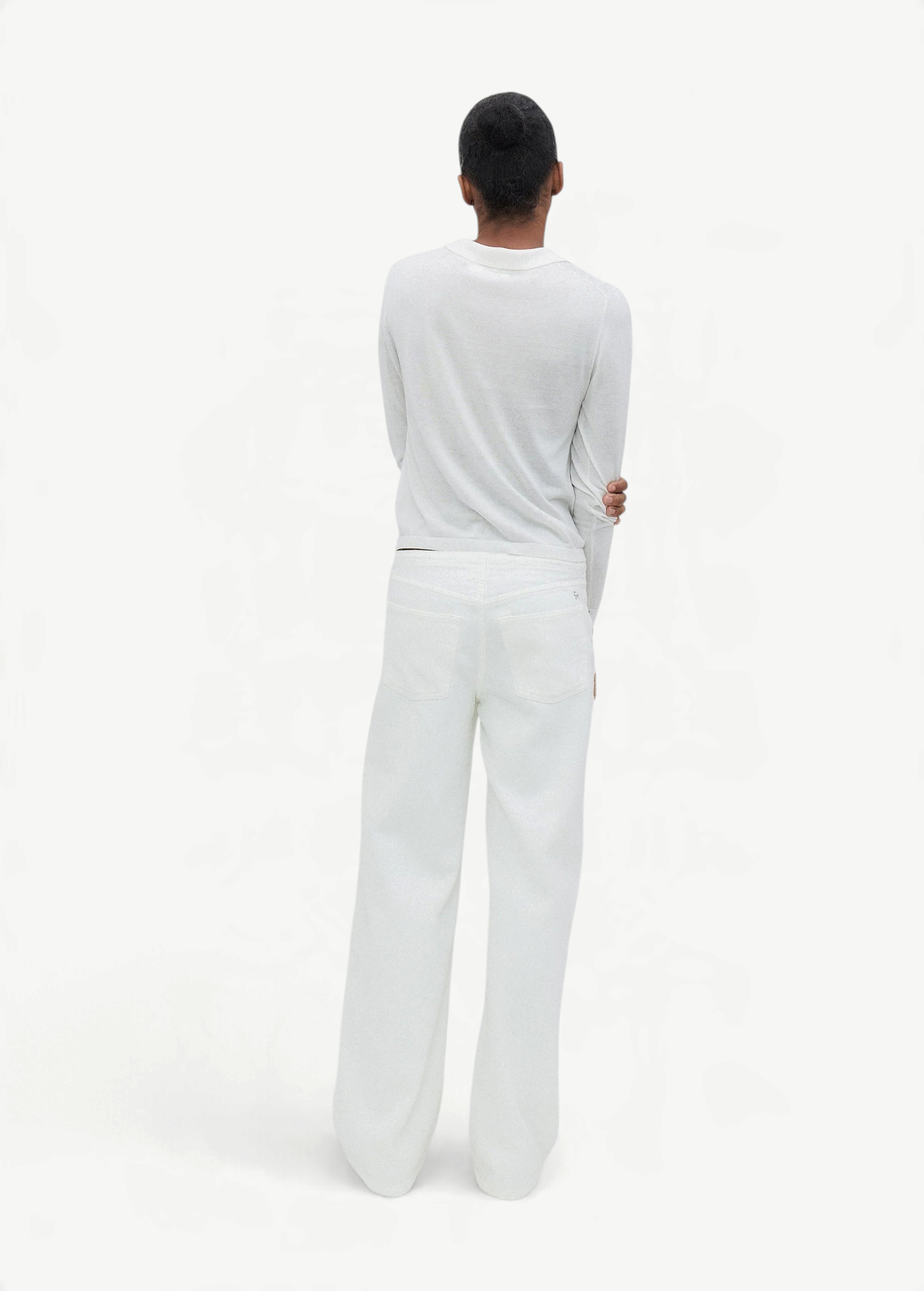 A person with short dark hair stands facing away, wearing a long-sleeve white shirt and the Cool Jean—a relaxed leg jean featuring an adjustable drawstring waist—set against a plain, light background.
