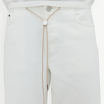 Wearing the Cool Jean in an off-white shade with a matching top, this look is cinched at the waist with a beige string belt featuring a round metallic front accent threaded through the waistband. The relaxed leg silhouette of the Cool Jean lends an effortlessly laid-back vibe to the outfit.